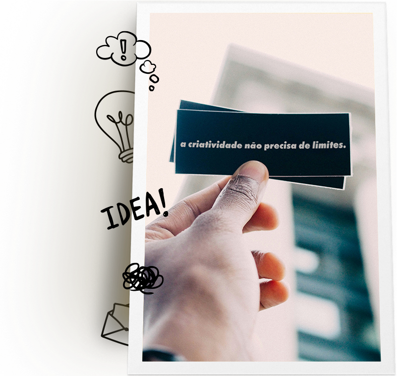 Mão segurando um cartão preto com a frase "a criatividade não precisa de limites" escrita em branco. Ao fundo, há uma estrutura arquitetônica desfocada. O lado esquerdo da imagem contém desenhos de uma lâmpada, um ponto de exclamação e a palavra "IDEA!" em preto.